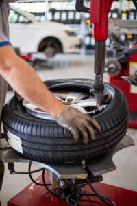 Leistungen Close-up of an auto mechanic changing a tire with precision equipment in a professional workshop.